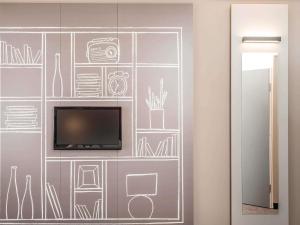 a wall with a tv and drawings on it at ibis Lyon Centre in Lyon