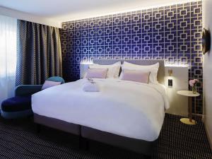 a bedroom with a large white bed and a blue wall at Grand Hotel Bregenz - MGallery Collection in Bregenz