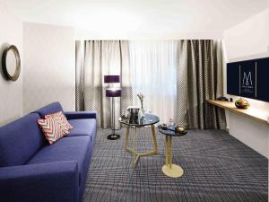 a living room with a blue couch and a table at Grand Hotel Bregenz - MGallery Collection in Bregenz