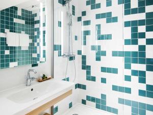 a bathroom with a sink and a shower with blue and white tiles at Grand Hotel Bregenz - MGallery Collection in Bregenz