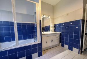 ein blau gefliestes Bad mit einer Badewanne und einem Waschbecken in der Unterkunft Villa Ici et Ailleurs, entre mer et forêt in La Tranche-sur-Mer + 29 Fotos