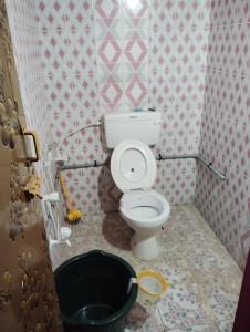 ein Badezimmer mit einem WC und einem schwarzen Eimer in der Unterkunft Kirubai Homestay in Tiruchchendūr