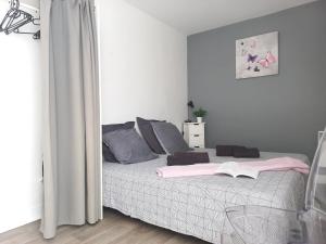 a bedroom with a bed with pink and gray pillows at L'Appart Sud Vendée in Saint-Hilaire-des-Loges