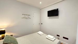ein weißes Schlafzimmer mit Bett und Flachbildfernseher in der Unterkunft Habitaciones en Toledo in Madrid