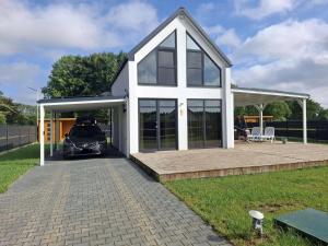 a house with a car parked in front of it at Ferienhaus Sophia 70qm bis 5 Gäste mit Fass-Sauna, Whirlpool April bis Oktober, 75qm Terrasse und eingezäunten Garten in Sierosław