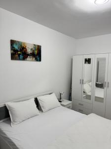 a white bedroom with a bed and a mirror at A B V Central Apartament in Râmnicu Vâlcea