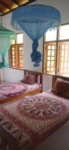 two beds in a room with windows at Ovinro rest - Anuradhapura in Anuradhapura