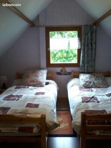 a bedroom with two beds and a window at Le chalet des Robins in La Bergerie