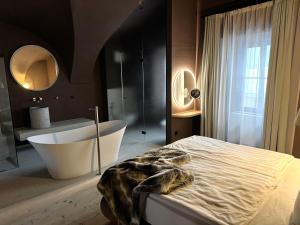 une chambre avec une baignoire et un lit et une salle de bain dans l'établissement La Maison 35 - Bruneck - zentral gelegene Appartments, à Brunico 40 autres photos