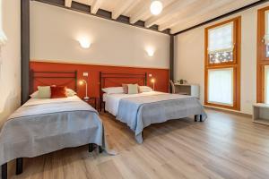 two beds in a room with wooden floors at La Montagnola in Castelfranco Veneto