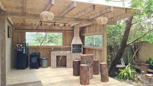 a wooden pergola with a fireplace in a backyard at Arte da Tribo Hostel & Camping in Praia do Rosa