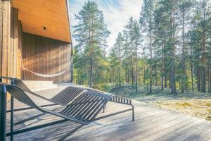 a bench on a porch with a view of the woods at Hideout Villa Jäkälä in Rokua +19 photos