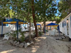 un patio avec des tables et des parasols à côté d'un bâtiment dans l'établissement Happy Camp Mobile Homes in El-Bahira Camping Village, à San Vito Lo Capo