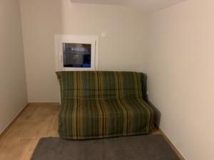 a green couch sitting in a room with a tv at Petit appartement dans une maison au calme in Bonneville