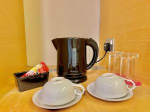 a coffee pot and two saucers on a table at NuEmpire Subang Suite - Empire Hotel in Subang Jaya