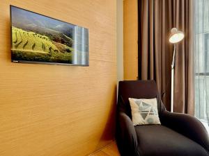 a room with a chair and a tv on the wall at NuEmpire Subang Suite - Empire Hotel in Subang Jaya +7 photos