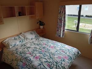 - une chambre avec un lit avec une couette à fleurs et une fenêtre dans l'établissement Beautiful and Spacious Mobile home - Sleeps 6,, à Clacton-on-Sea