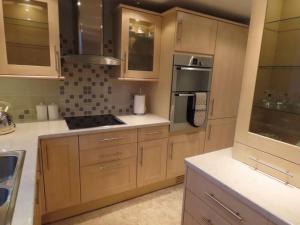 a kitchen with wooden cabinets and stainless steel appliances at The Flat in Broughton +8 photos