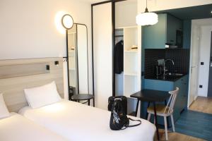a hotel room with a bed and a small kitchen at Aparthotel Adagio Access Porte de Camargue in Saint-Martin-de-Crau +55 photos
