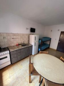 a kitchen with a table and a white refrigerator at El Dorado Deptos a una cuadra del mar in San Bernardo
