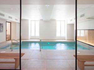 a swimming pool in a building with a pool at Hotel Mercure Parc du Coudray - Barbizon in Le Coudray-Montceaux