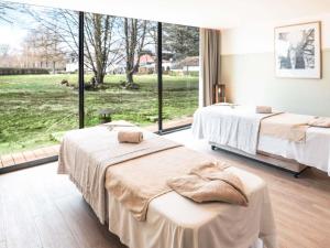 two beds in a room with a large window at Hotel Mercure Parc du Coudray - Barbizon in Le Coudray-Montceaux