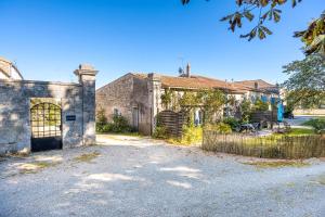an old stone house with a gate and a fence at Le Colombier Gites in Surgères