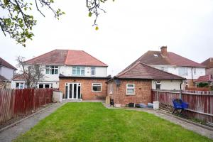 a house with a fence and a yard at Spacious 4-Bed Home with Free Parking in Heston