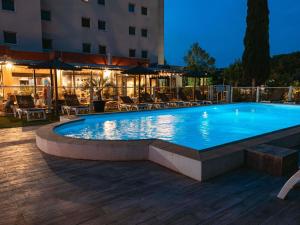 a large swimming pool with chairs and a building at ibis Marseille Provence Aéroport in Marignane