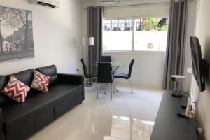 un salon avec un canapé noir et une table dans l'établissement 2 Bed Apartment Sleeps 6 -Public pool and Patio, à La Cala de Mijas