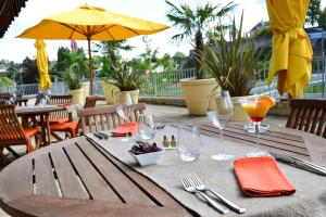 a wooden table with drinks and wine glasses on a patio at Mercure Saint Lô Centre in Saint Lo