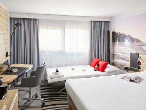 a hotel room with two beds and a desk at Novotel Birmingham Airport Terminal Building - NEC in Bickenhill