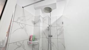 a shower in a bathroom with white tiles at Next to Coco's Apartment in Tirana +27 photos