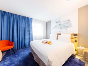 a hotel room with a large bed and a red chair at Mercure Paris Massy Gare TGV in Massy +91 photos