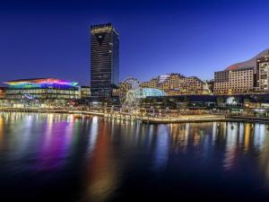 a view of a city at night from the water at Novotel Sydney Darling Harbour in Sydney
