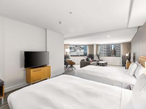 a hotel room with two beds and a flat screen tv at Novotel Sydney Darling Harbour in Sydney +251 photos