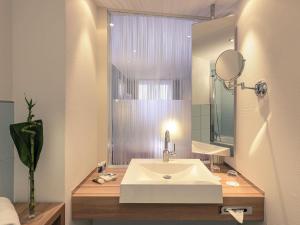 a bathroom with a sink and a mirror at Mercure Residenz Frankfurt Messe in Frankfurt/Main +92 photos