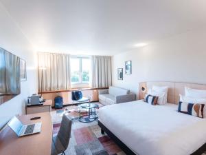 a hotel room with a large bed and a desk at Mercure Besancon Parc Micaud - Hotel & Bar in Besançon