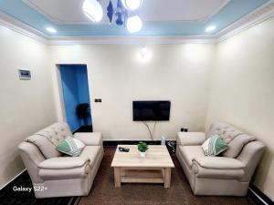 ヤウンデにあるClimatisation - Wi-Fi gratuitのソファ2つとテレビのあるリビングルーム +2枚の写真