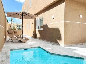 a swimming pool with an umbrella next to a building at Modern Escape Villa in St Julian w Pool by ArcoCollection in St. Julianʼs