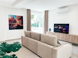 a living room with a couch and a tv at Modern Escape Villa in St Julian with Pool by ArcoBnb in St Julian's