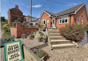 a brick house with a sign in front of it at Little Lodge B&B Lutterworth in Lutterworth