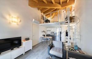 a living room with a tv and a staircase in a room at Relais Fasanella attico - Lago di Garda in Toscolano Maderno