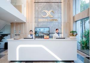 two people sitting at a reception desk in a lobby at X-Digital HOTEL in Bắc Ninh