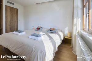 a white bedroom with a large bed with towels on it at Le Praelatenberg - La Maison des Vignerons in Orschwiller
