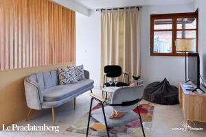 a living room with a couch and a chair and a television at Le Praelatenberg - La Maison des Vignerons in Orschwiller