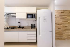 a white kitchen with white cabinets and a refrigerator at Edifício Mosaico do Mar - Seu Refugio na Praia da Jatiúca in Maceió