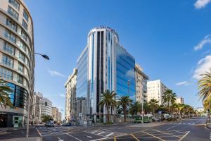 a tall glass building on a city street with palm trees at Eurostars Atlántida in Santa Cruz de Tenerife