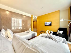 two beds in a hotel room with white sheets at NuEmpire Subang Suite - Empire Hotel in Subang Jaya
