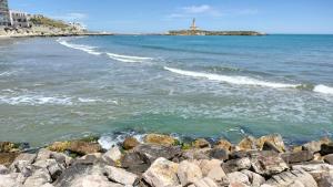 a rocky beach with a lighthouse in the distance at B&B Casa Desimio in Vieste